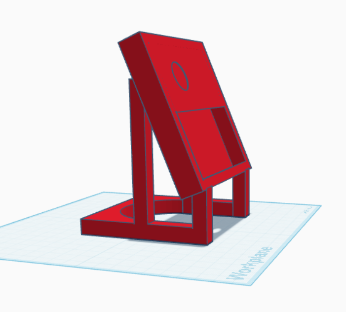 A red 3D-printed phone stand or tablet holder designed in Tinkercad, featuring an angled tilted platform with a small oval cutout, supported by a sturdy rectangular base with vertical support legs.